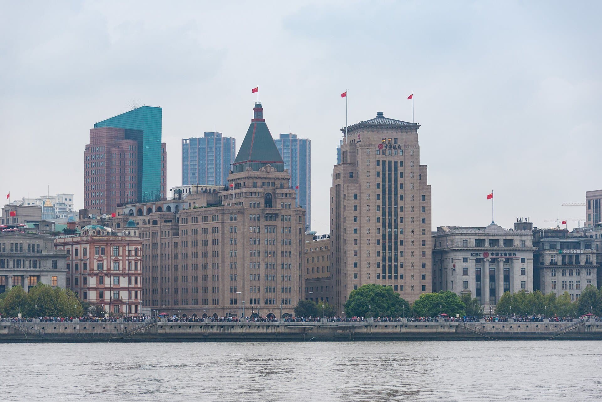 Historic stone buildings on Shanghai's Bund, including the green-roofed Peace Hotel and the Bank of China, seen across the Huangpu River