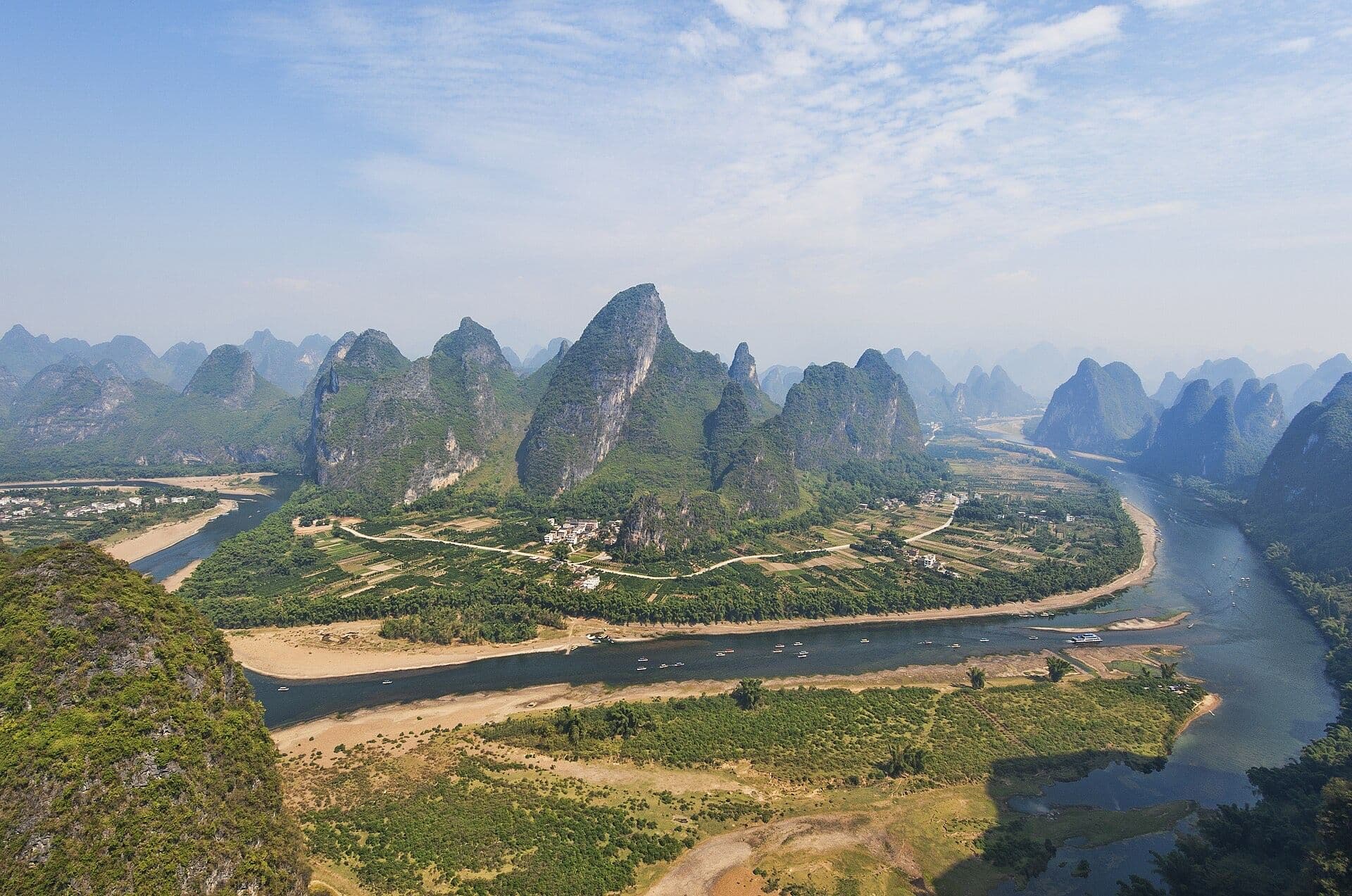 Li River winding past green karst peaks and farmland near Yangshuo, seen from a hilltop
