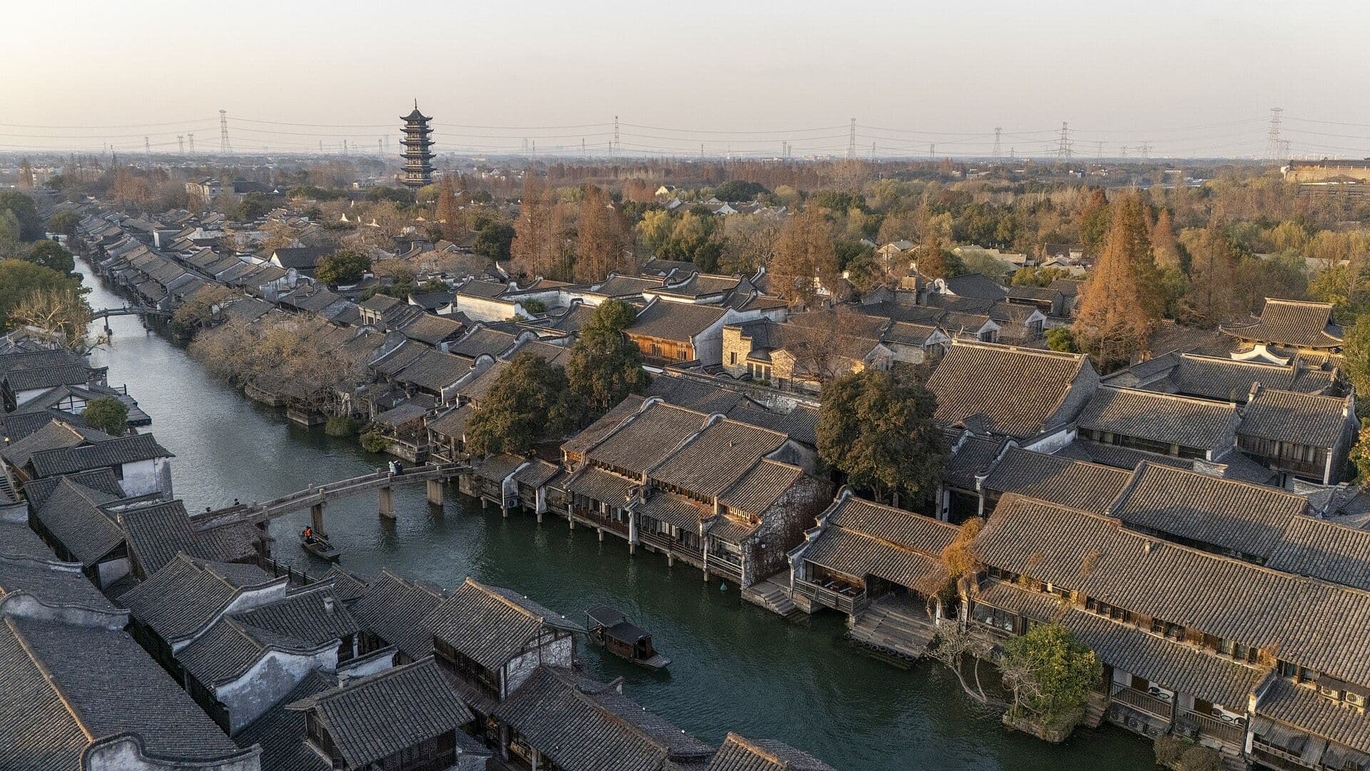 Aerial view of Wuzhen water town: a canal lined with grey-tiled old houses, a pagoda behind